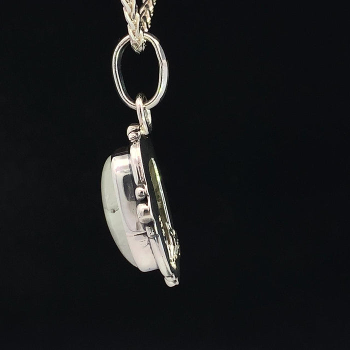 photo of a silver white moonstone pendant on a silver chain on a black background side view