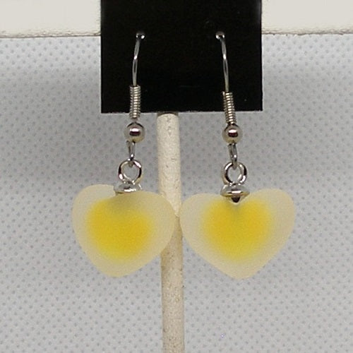 Heart-shaped yellow earrings on a black card against a white background