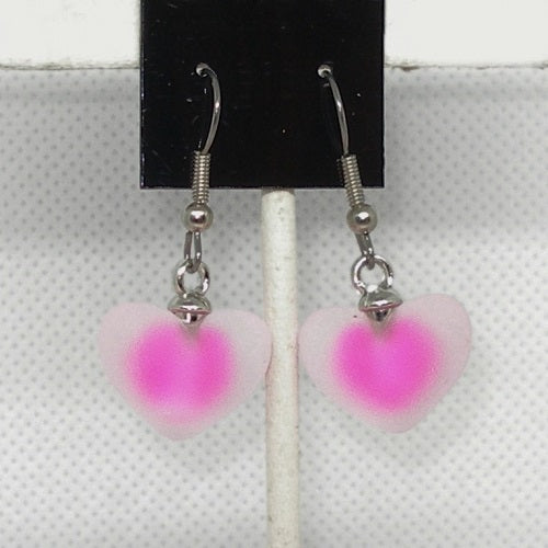 Pink heart-shaped earrings on a stand with a white background