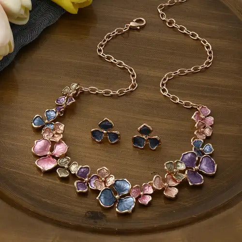 The Vivid Petale Set captures the poetry of spring through delicately shaped petals in soft pastel tones — lilac, rose, sky, and sage — all set in gleaming gold alloy. Designed to radiate joy and femininity, this floral necklace and earring duo adds a touch of artistry to every look, from brunches to weddings.
