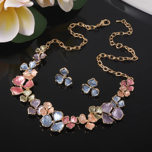 The Vivid Petale Set captures the poetry of spring through delicately shaped petals in soft pastel tones — lilac, rose, sky, and sage — all set in gleaming gold alloy. Designed to radiate joy and femininity, this floral necklace and earring duo adds a touch of artistry to every look, from brunches to weddings.