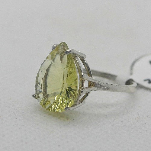 Ring with a pear-shaped yellow gemstone on a light gray background